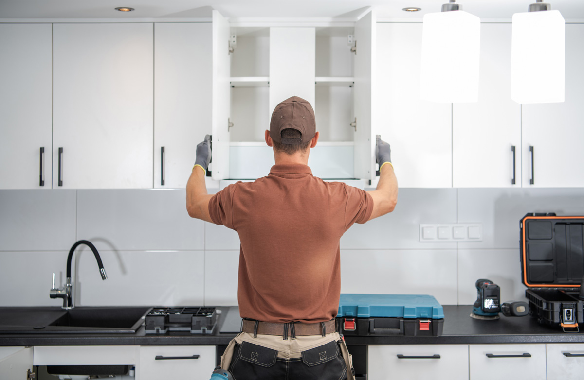 A man installing white custom cabinets in El Paso.